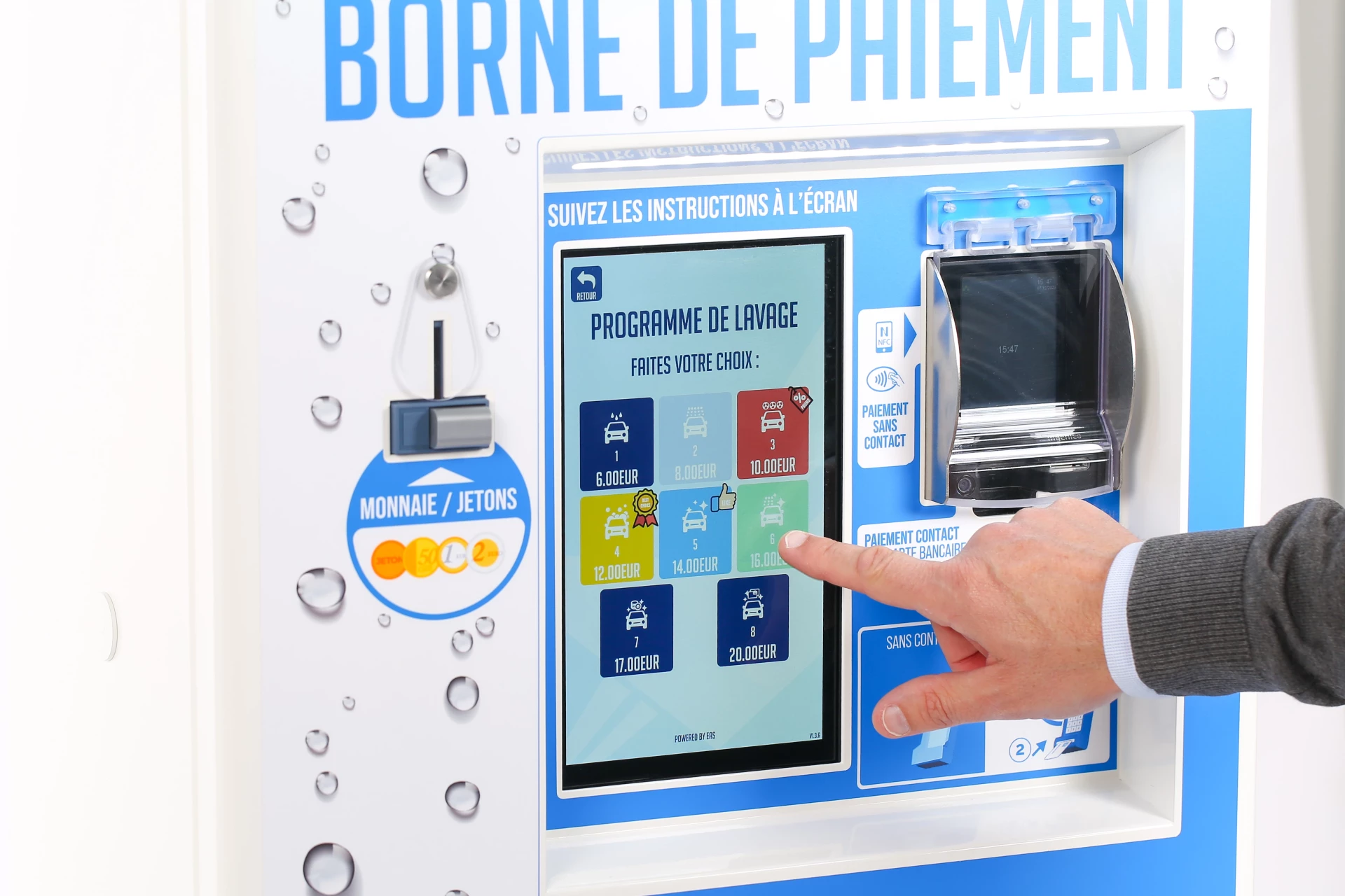 L'image montre une personne utilisant une borne de paiement pour laverie. La borne affiche des instructions et des options de